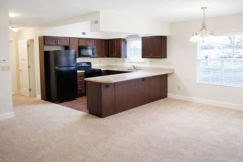 A kitchen with brown cabinets and a black refrigerator.