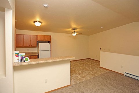 A kitchen area with a refrigerator, cabinets, and a counter.
