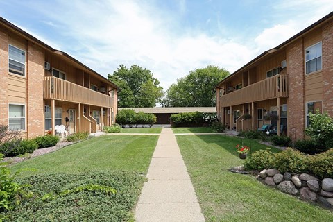 A long concrete walkway separates two rows of apartment buildings.