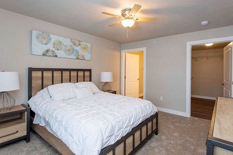 A bedroom with a bed, two lamps, and a ceiling fan.