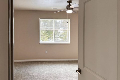A room with a window and a ceiling fan.