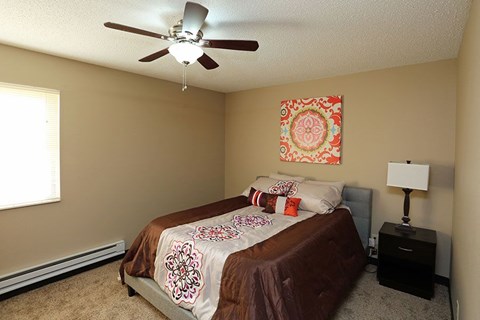A bedroom with a bed, a ceiling fan, and a lamp.