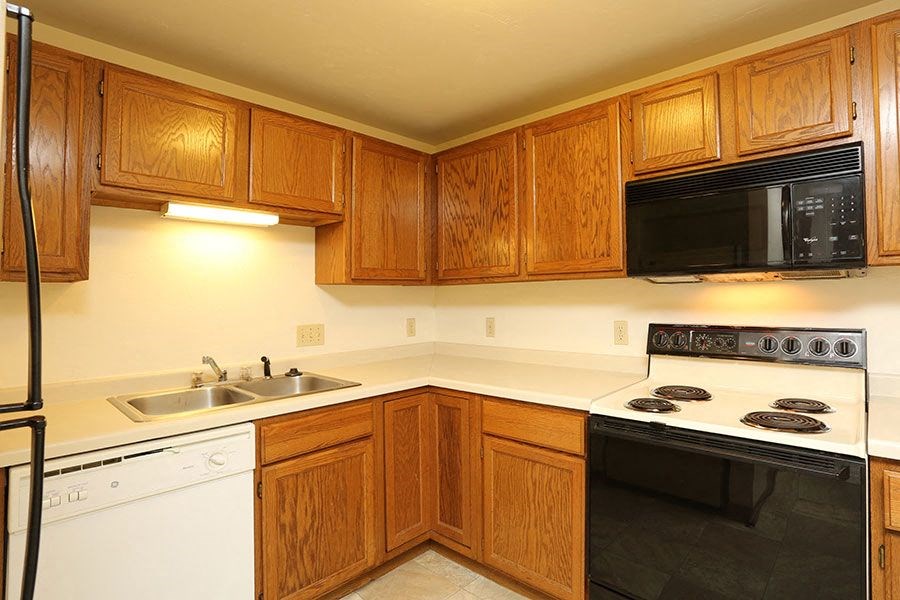 A kitchen with wooden cabinets and a black microwave above the stove.