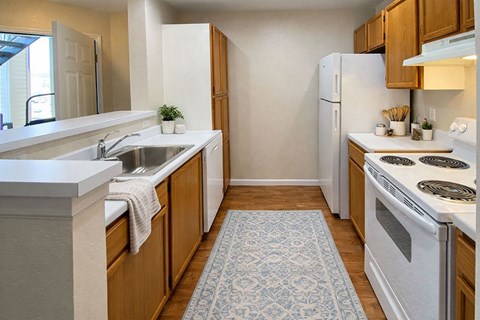 A kitchen with white appliances and wooden cabinets.