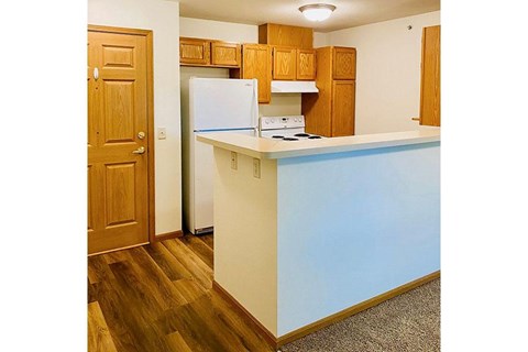 A kitchen with a white fridge and wooden cabinets.