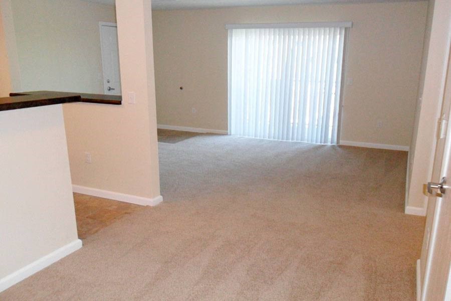 an empty living room and kitchen with a large window
