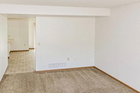 an empty living room with white walls and carpet