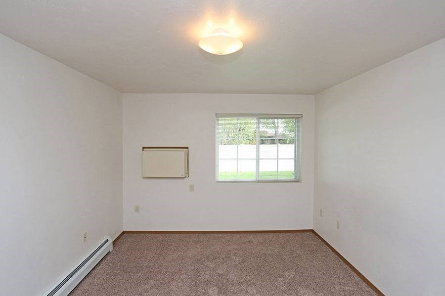 an empty living room with a window and carpet