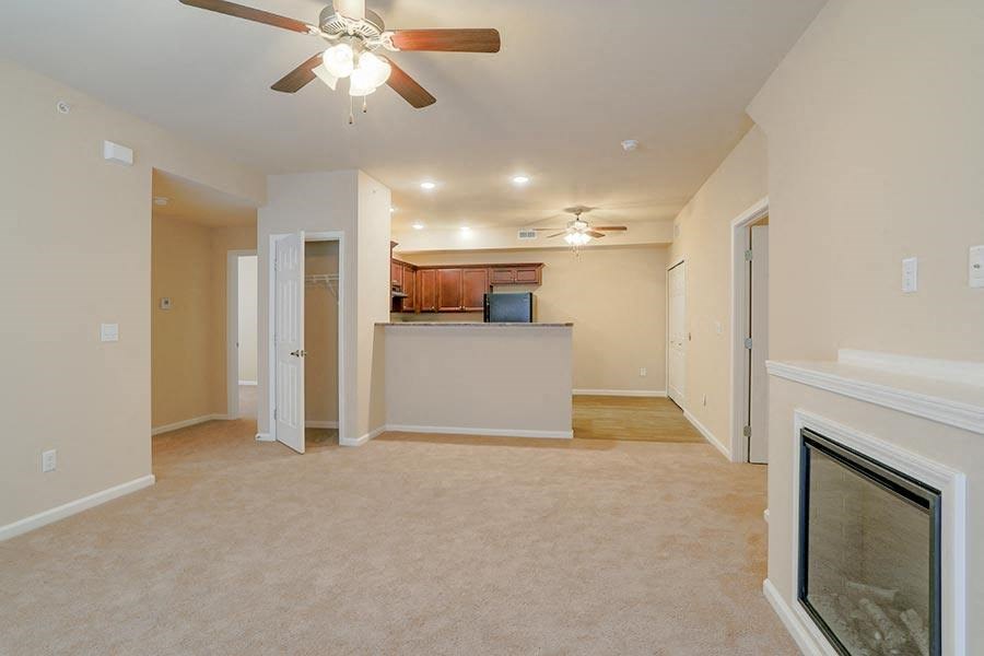 an empty living room with a ceiling fan and a fireplace