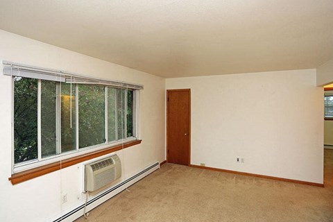 an empty living room with a large window and a radiator