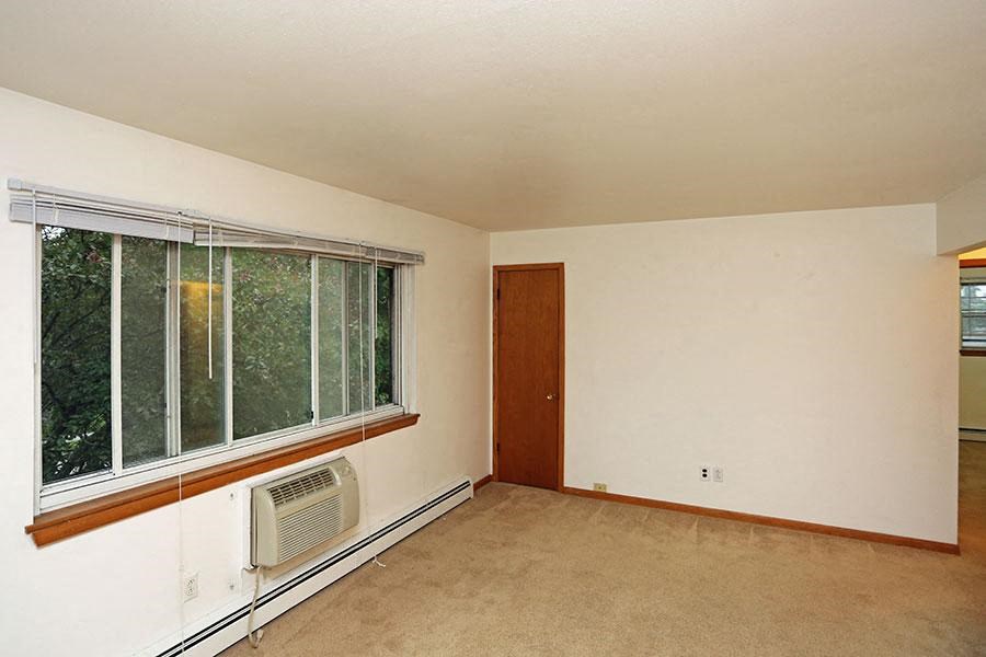 an empty living room with a large window and a radiator