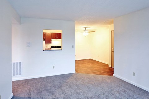 an empty living room with white walls and a kitchen