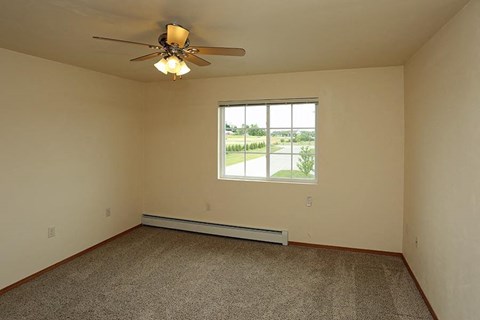 an empty living room with a ceiling fan and a window