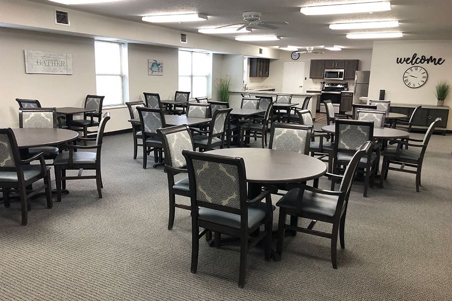 a large dining room with tables and chairs and a kitchen