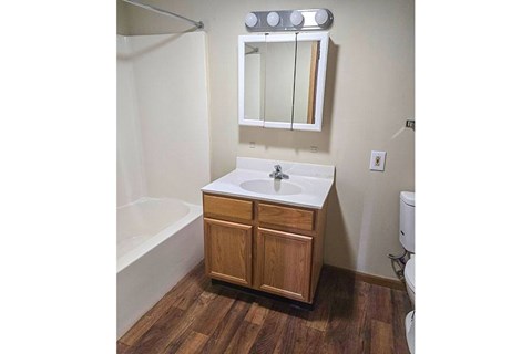 A bathroom with a wooden vanity and a white sink.