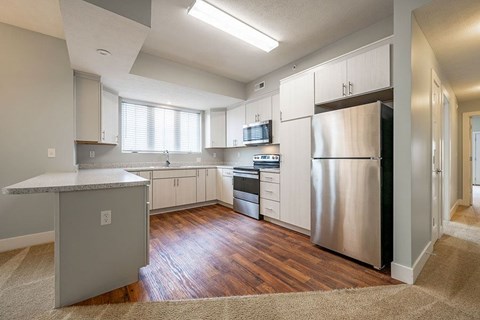 A kitchen with a stainless steel refrigerator and wooden floors.