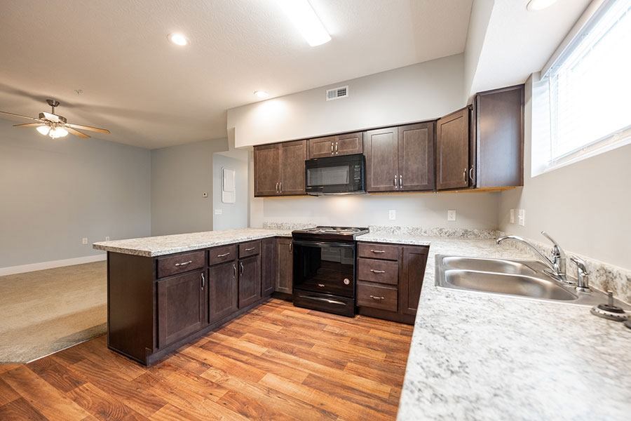 A kitchen with dark wood cabinets and a white marble countertop.