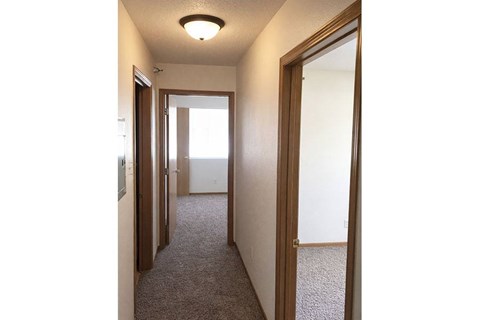 A hallway with a carpeted floor and white walls.