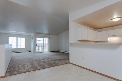 an empty living room with white cabinets and a door