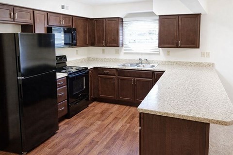A kitchen with dark wood cabinets and a black refrigerator.