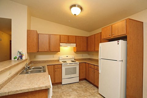 A kitchen with white appliances and wooden cabinets.