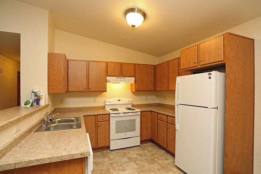 A kitchen with a white refrigerator, white stove, and white oven.