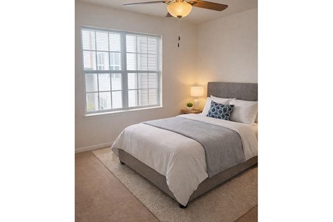 A bedroom with a bed, a ceiling fan, and a window.