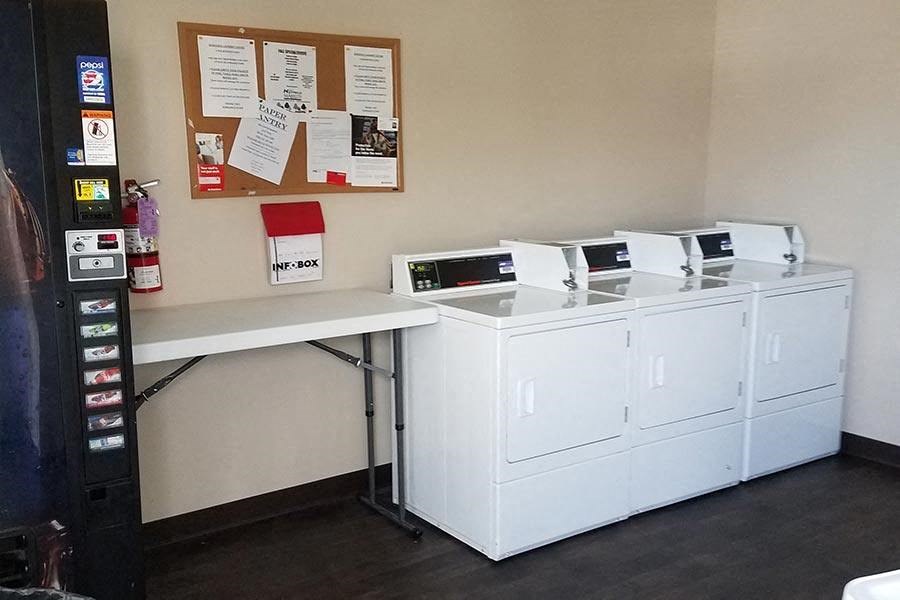 A white desk with a bulletin board and a vending machine on the left.