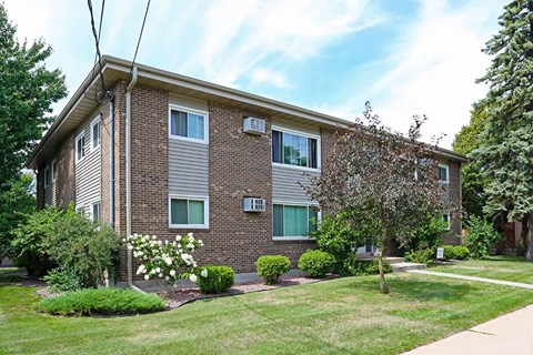 A brick apartment building with a green lawn in front.