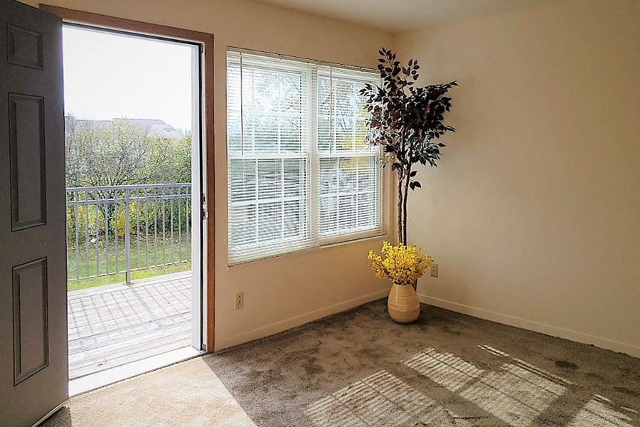 a room with a vase with flowers on the floor and a door