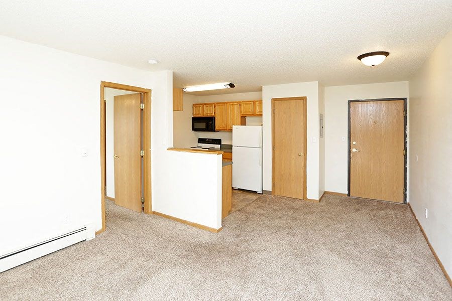 an empty room with a kitchen and a living room