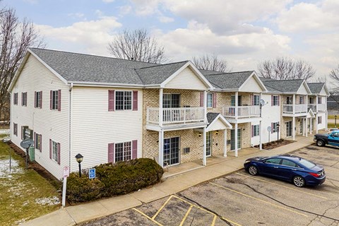 A white building with a blue car parked in front.