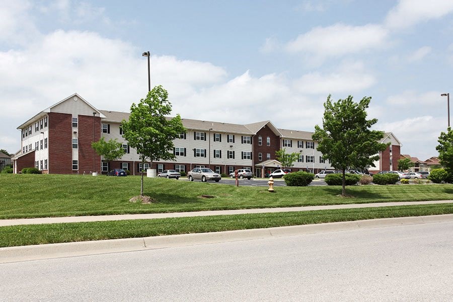 A large red brick building with a green tree in front.