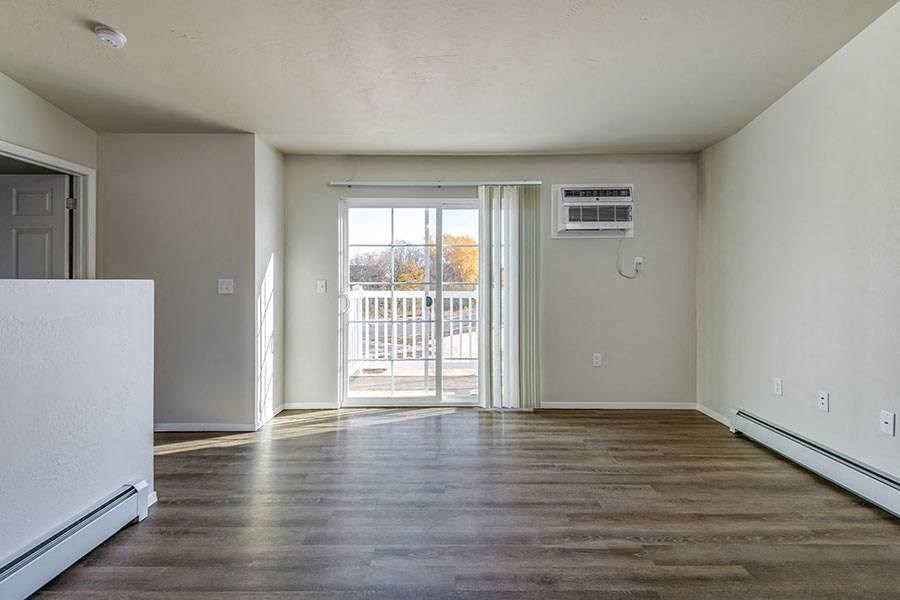 an empty living room with a door to a balcony