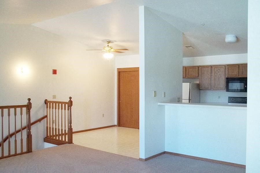 an empty living room with a kitchen and a staircase