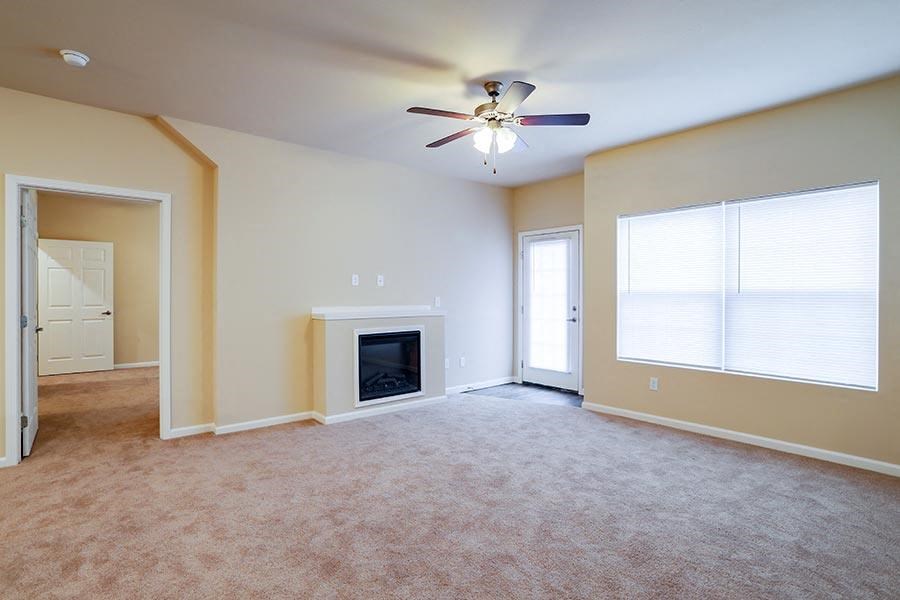 an empty living room with a ceiling fan and a fireplace