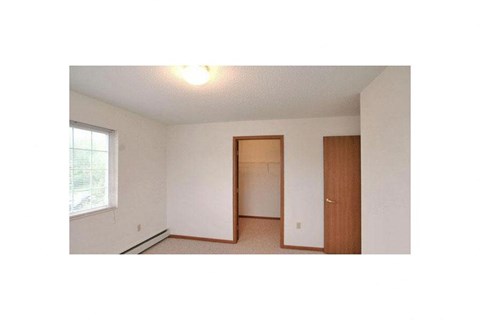an empty bedroom with a door to a closet