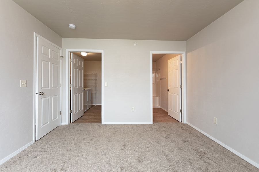 an empty room with a hallway to a bedroom and a bathroom