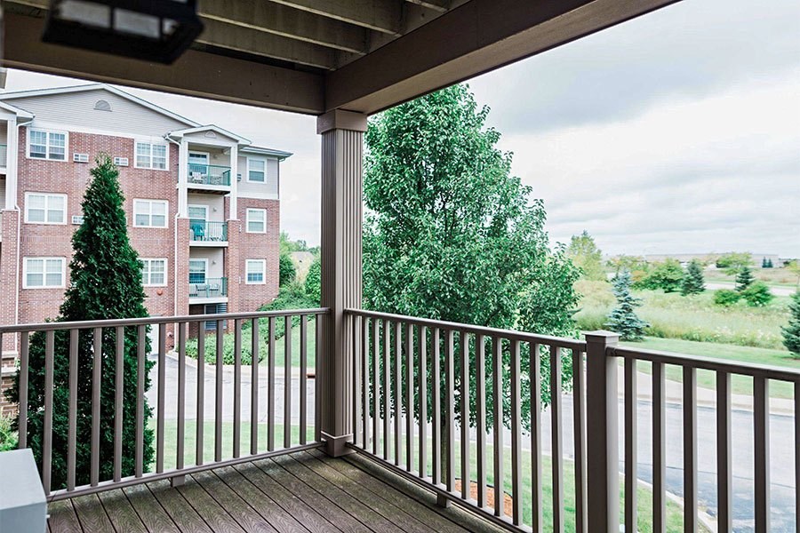 A balcony with a railing and a view of a building and trees.