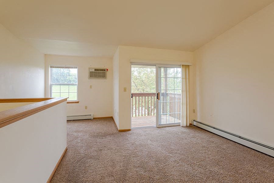 an empty living room with a door to a balcony