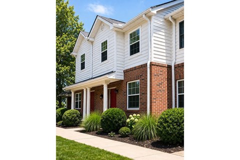 A white house with a red door and brick pillars.