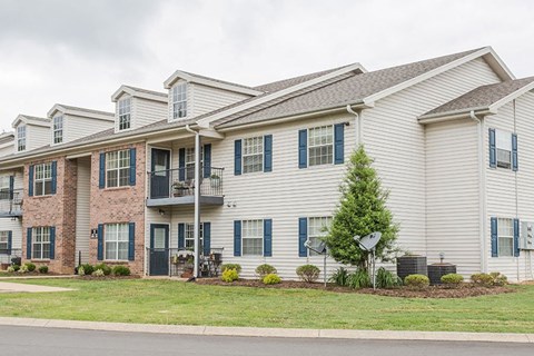 the exterior of an apartment building with a yard and grass