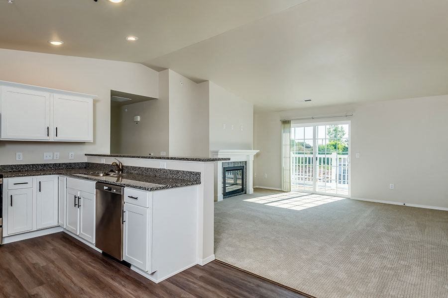 an empty kitchen and living room with white cabinets