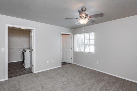 an empty living room with a ceiling fan and a closet