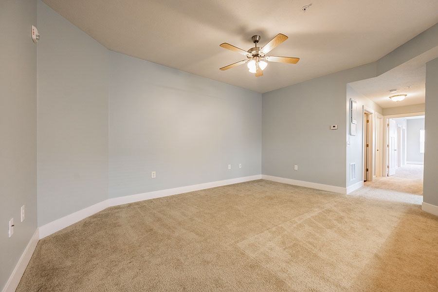 A room with a ceiling fan and carpeted floor.