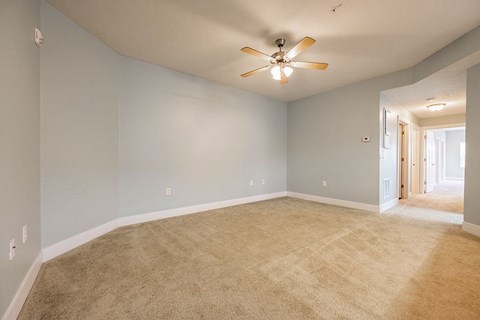 A room with a ceiling fan and carpeted floor.