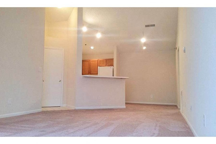 an empty living room with a kitchen in it