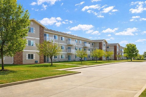 Apartment complex with a parking lot in front.
