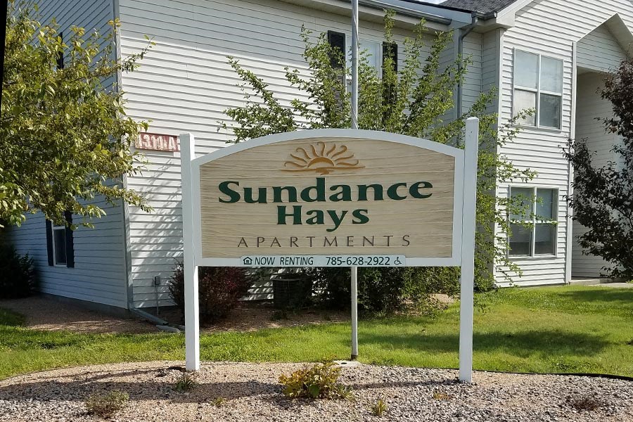 A sign for Sudance Hays Apartments is displayed in front of a building.