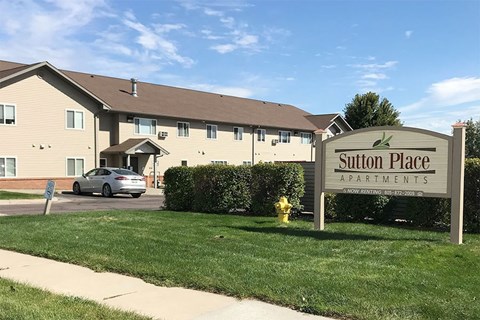 A sign for Sutton Place Apartments stands in front of a building.